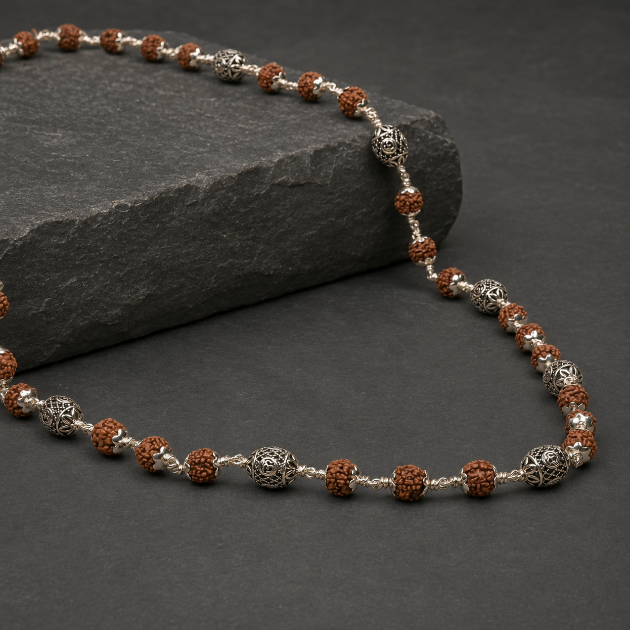 Close-up of oval Om 925 silver beads and Rudraksha texture