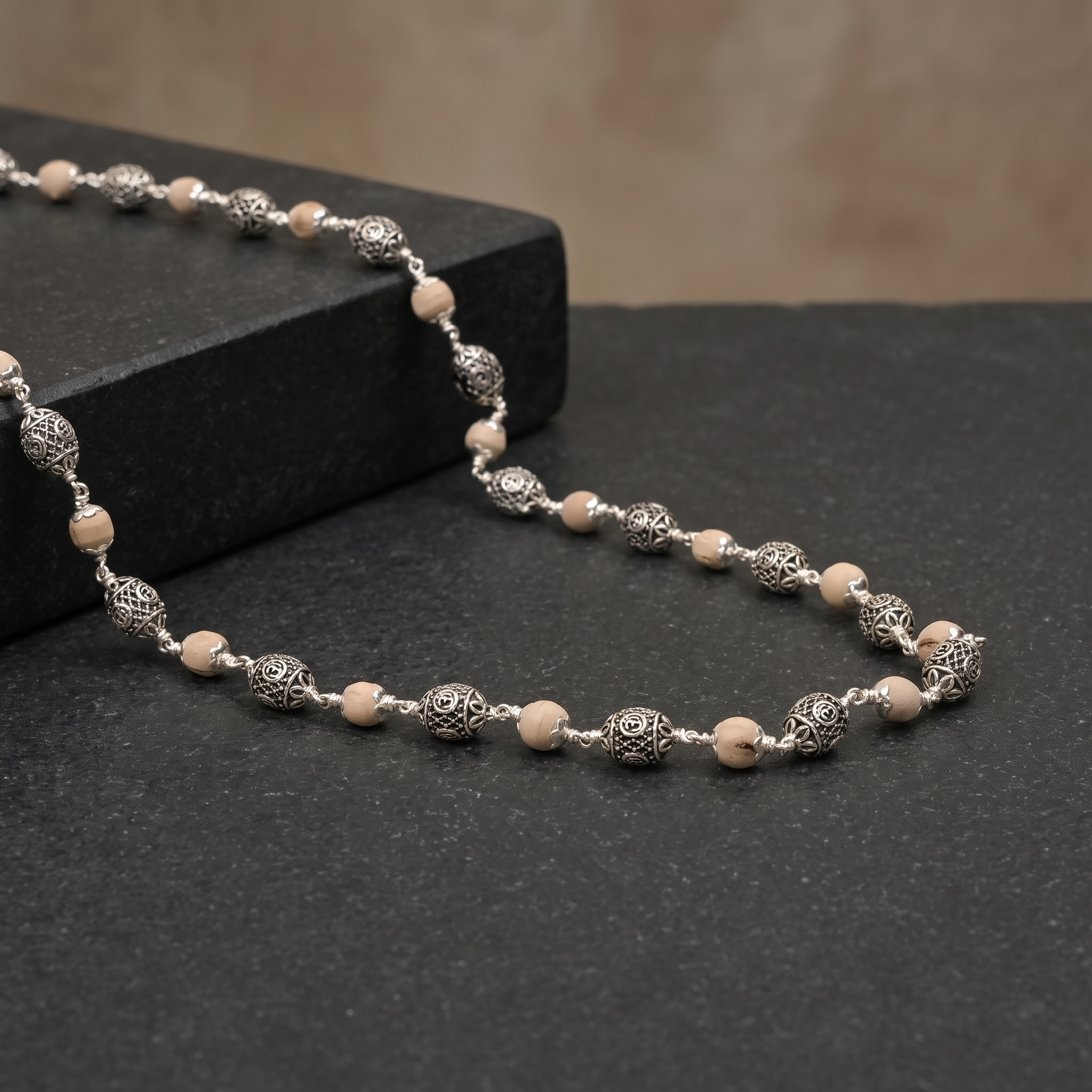 Close-up of oval Om silver beads on Tulsi mala